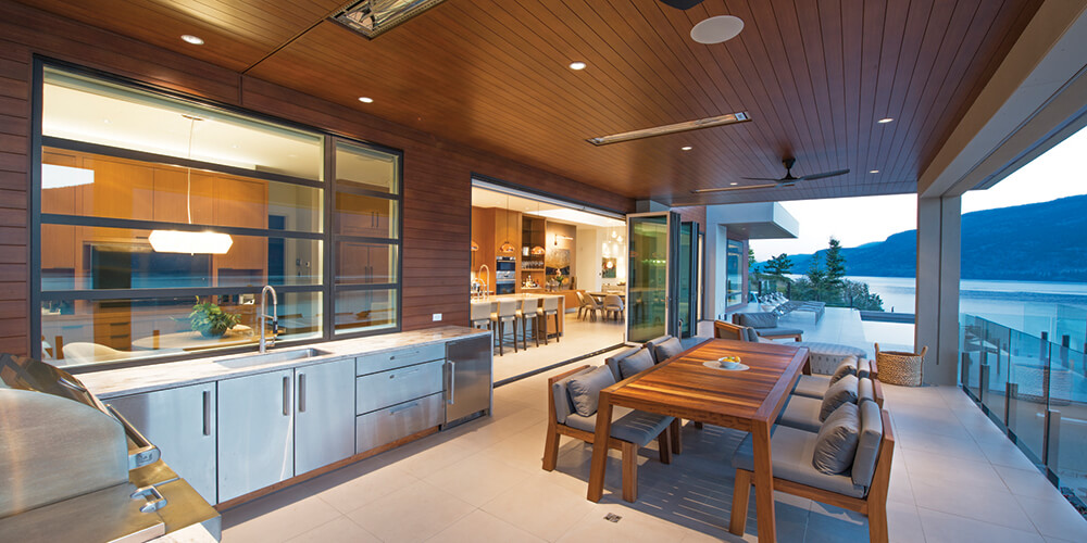 Folding doors open up the living space to an outdoor kitchen and dining area with additional seating for guests. AD905